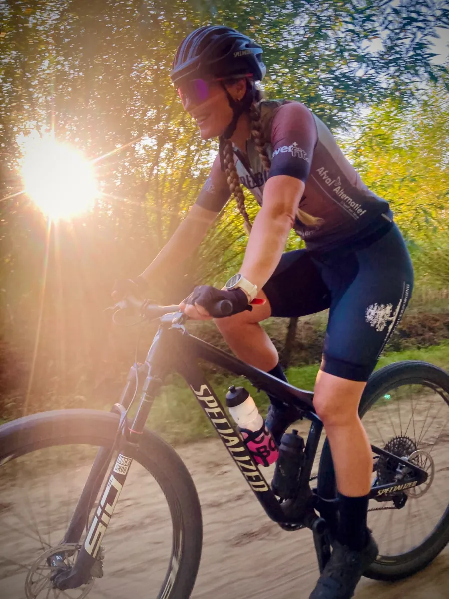 Een fietser in het REEBOK-clubshirt met de zon achter zich.