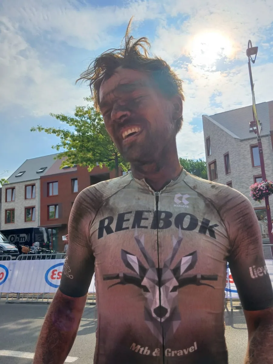 Een clubfietser met een modderig gezicht en REEBOK-shirt na een rit.