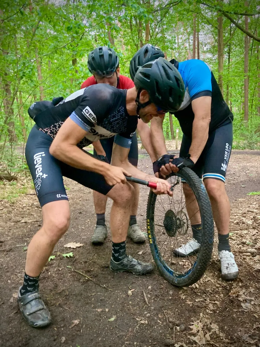 Twee fietsers helpen elkaar bij het herstellen van een fietswiel.