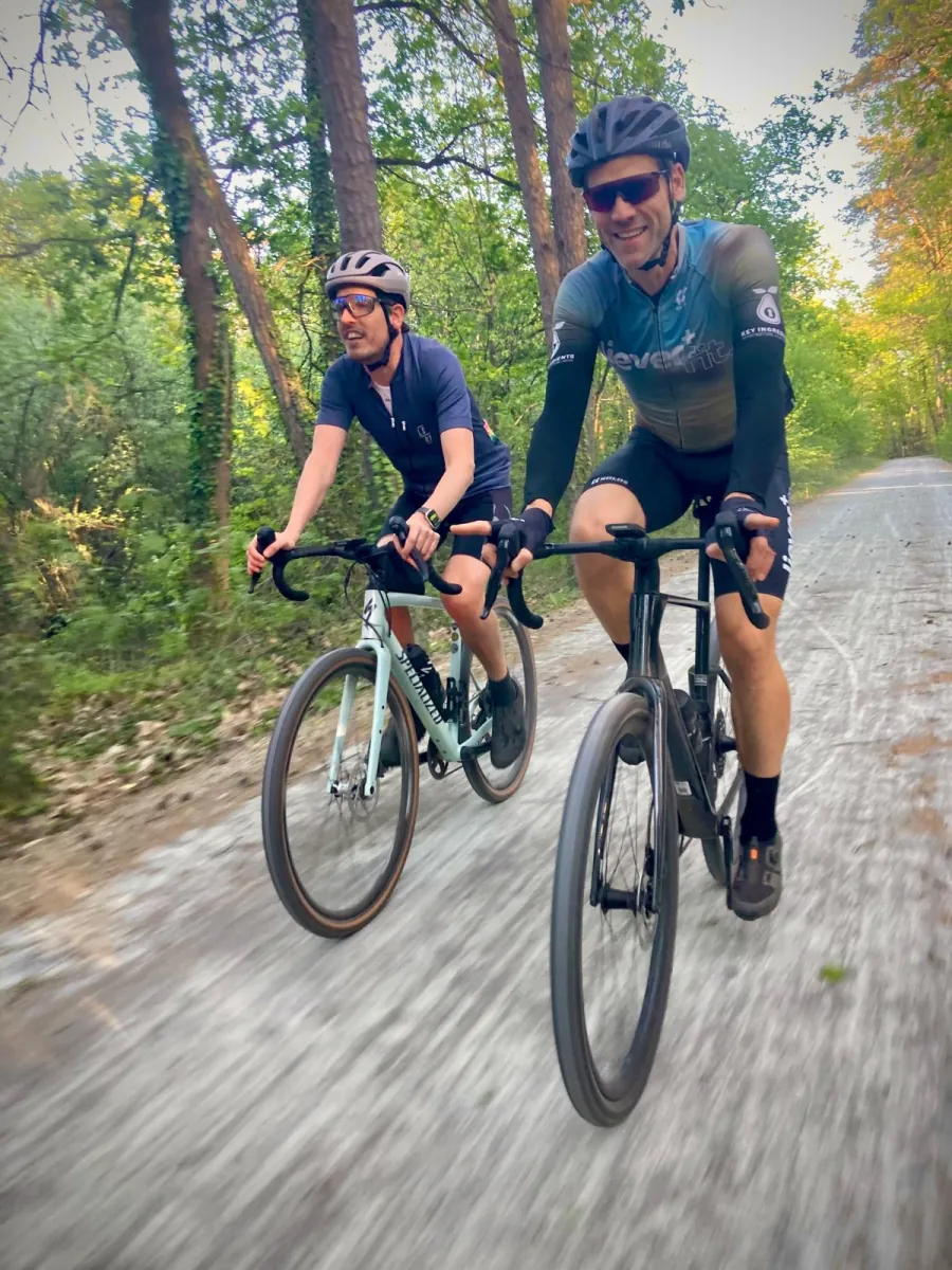 Twee fietsers rijden naast elkaar over een pad door het bos.