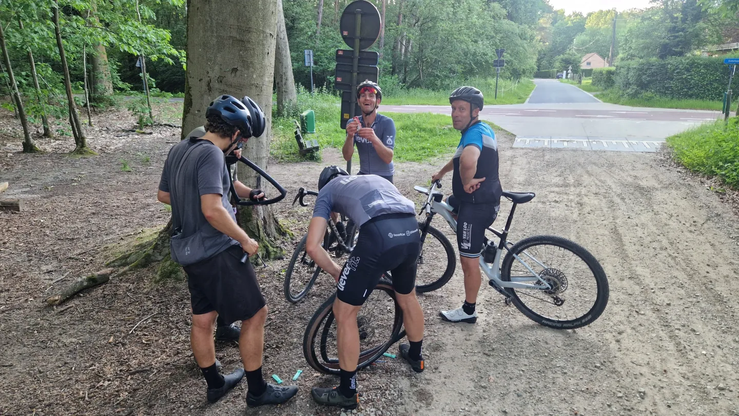 Een groep fietsers houdt halt bij een boom langs een bospad.